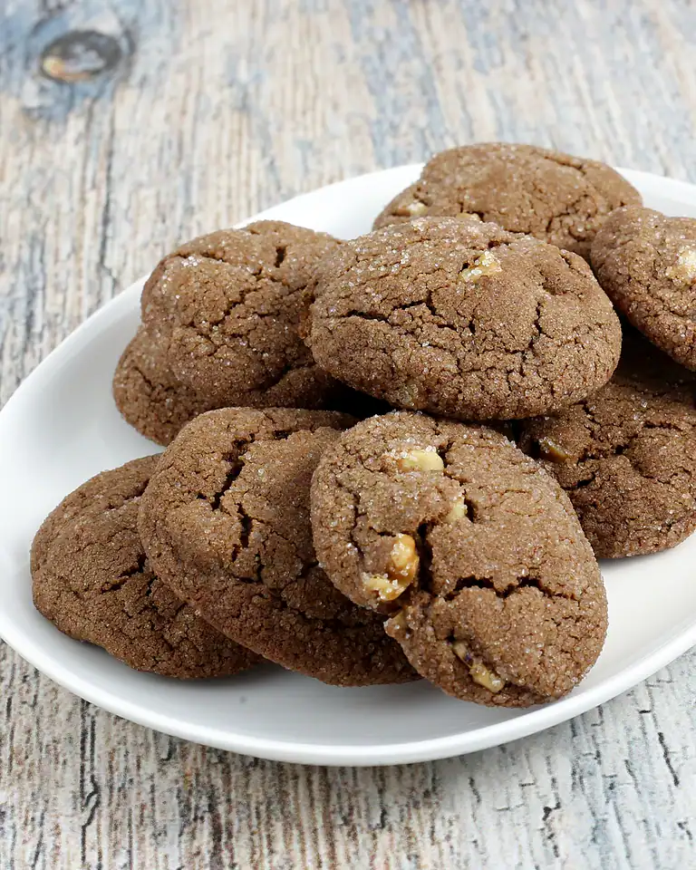 Fudgy chocolate cookies with chopped nuts on white plate.