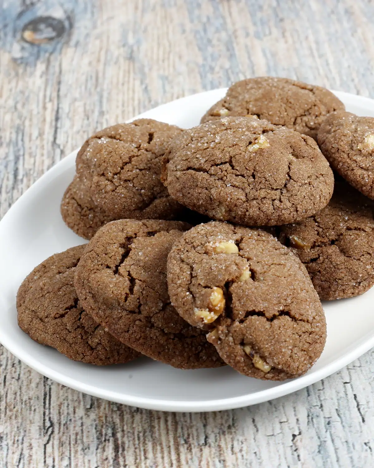 Fudgy chocolate cookies with chopped nuts on white plate.