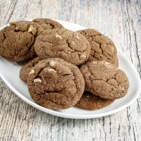 Fudgy chocolate cookies with white chocolate chips on white dish.