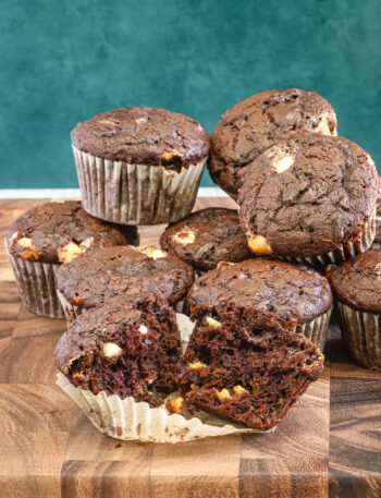 Chocolate zucchini muffins with white chocolate chips, baked, with one split to show the texture.