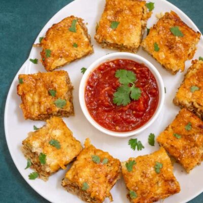Chorizo sausage quiche squares on a platter with salsa.