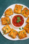 Platter of chorizo appetizer squares with salsa for dipping.