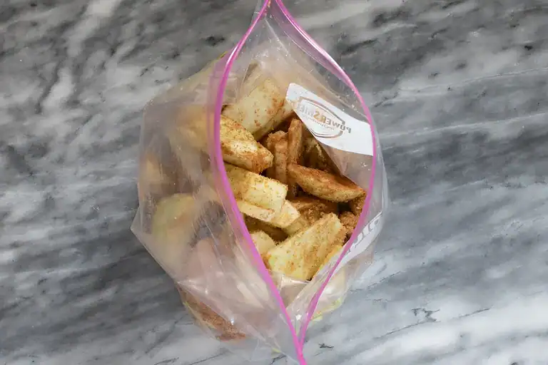 Crunchy apple slices with cinnamon inside a resealable plastic bag.