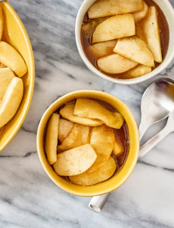 Cinnamon apples in small bowls with spoons.
