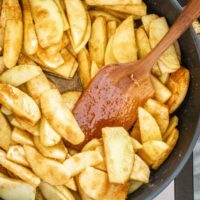 Golden fried apple slices in a skillet with caramel sauce.