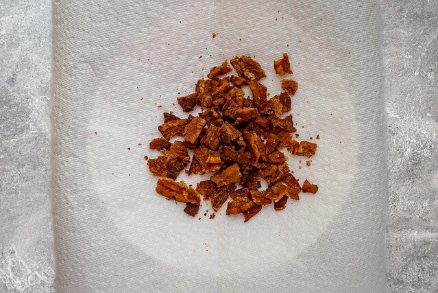 Crumbled cooked bacon on a paper towel.