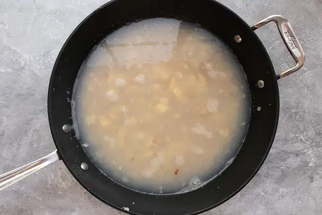 Simmering the clams and potatoes in clam juice and water for clam and corn chowder.