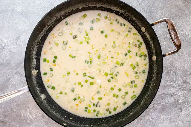 Finishing the clam and corn chowder with evaporated milk and green onions.