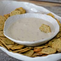 A bowl of crackers with clam dip for dipping.