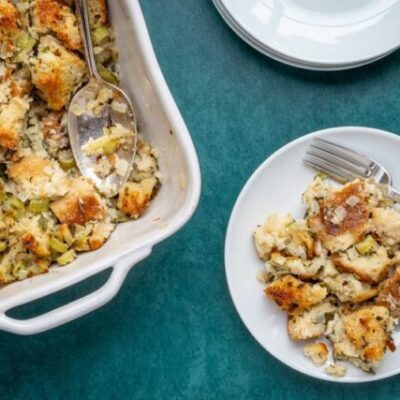 bread stuffing or dressing on a plate with baking dish on the side