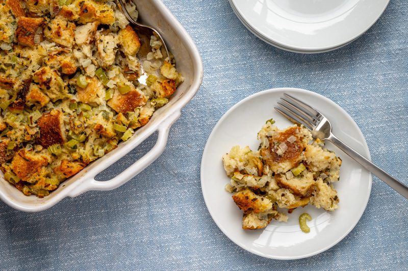 A small plate of bread stuffing with baking dish on the side