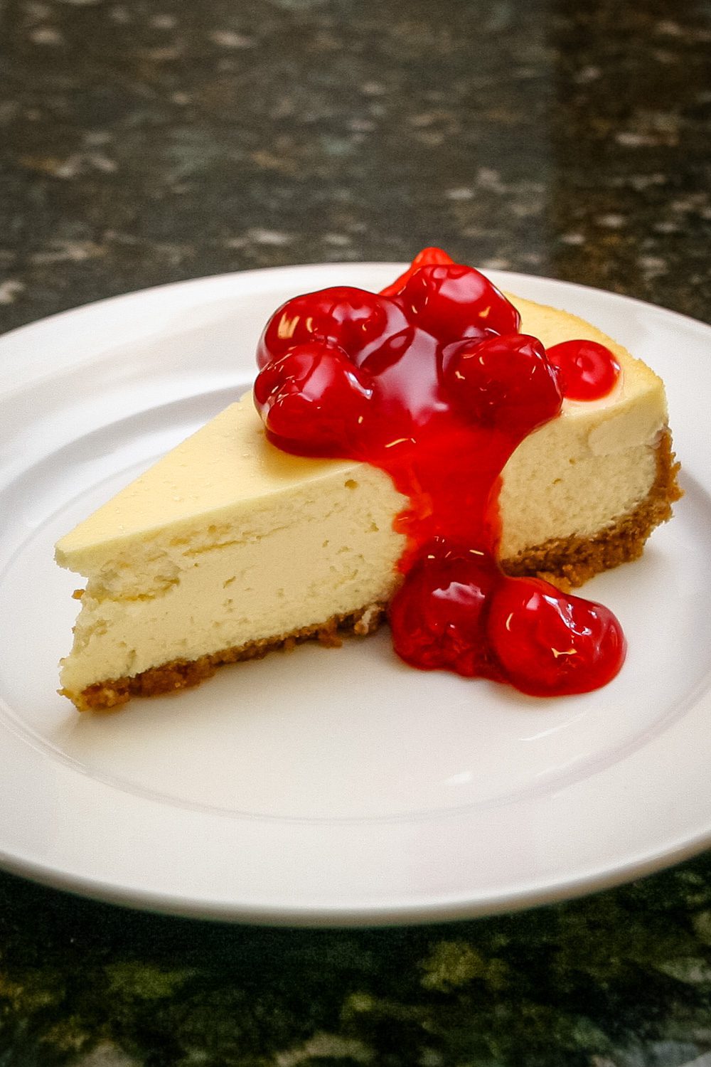 A slice of classic cheesecake with a garnish of cherry pie filling