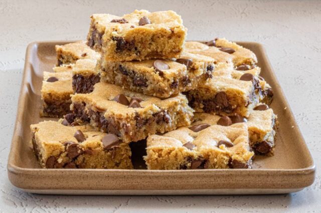 Chocolate chip cookie bars, sliced and stacked on a platter.