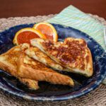 A serving of sliced French toast with orange slices on the side.