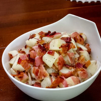 Crispy bacon and potatoes in a white bowl.