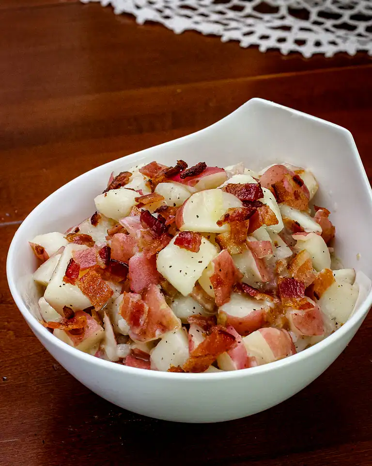 Crispy bacon and potatoes in a white bowl.