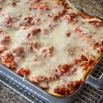 Homemade easy lasagna in a baking dish on a cooling rack.