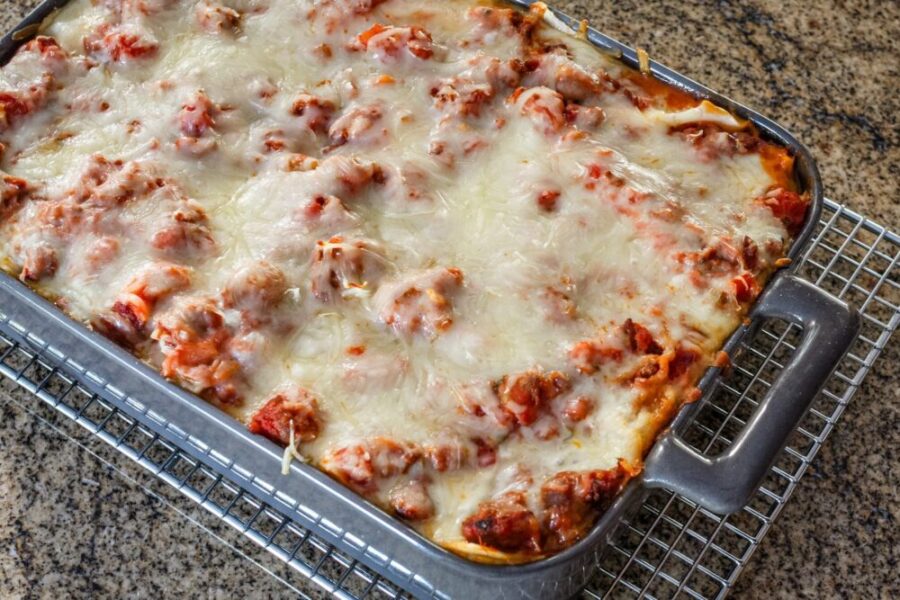 Homemade easy lasagna in a baking dish on a cooling rack.