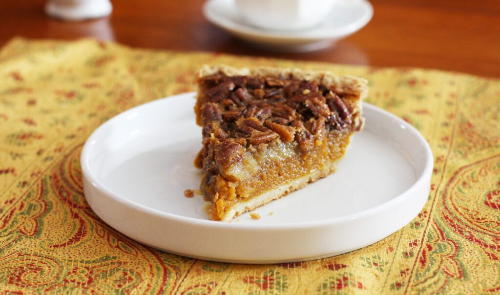 A generous slice of pumpkin pecan pie on a plate