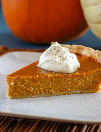 a slice of classic pumpkin pie with whipped cream and a sprinkle of nutmeg