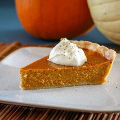 a slice of classic pumpkin pie with whipped cream and a sprinkle of nutmeg