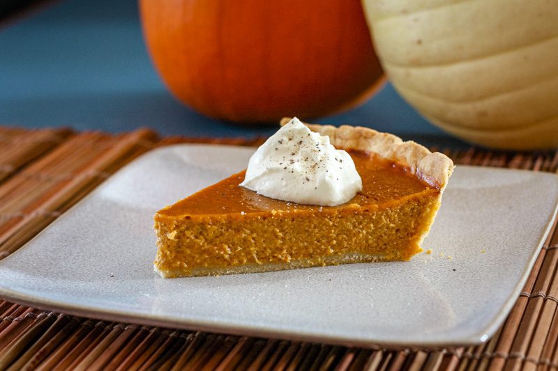 a slice of classic pumpkin pie with whipped cream and a sprinkle of nutmeg