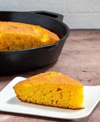 classic american cornbread on a plate with a skillet in the background