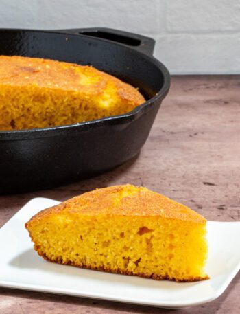 classic american cornbread on a plate with a skillet in the background