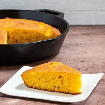 classic american cornbread on a plate with a skillet in the background