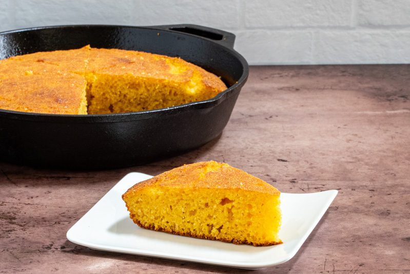 classic american cornbread on a plate with a skillet in the background
