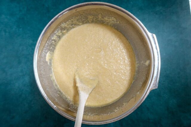 Making cornbread batter in the bowl with a wooden spoon.
