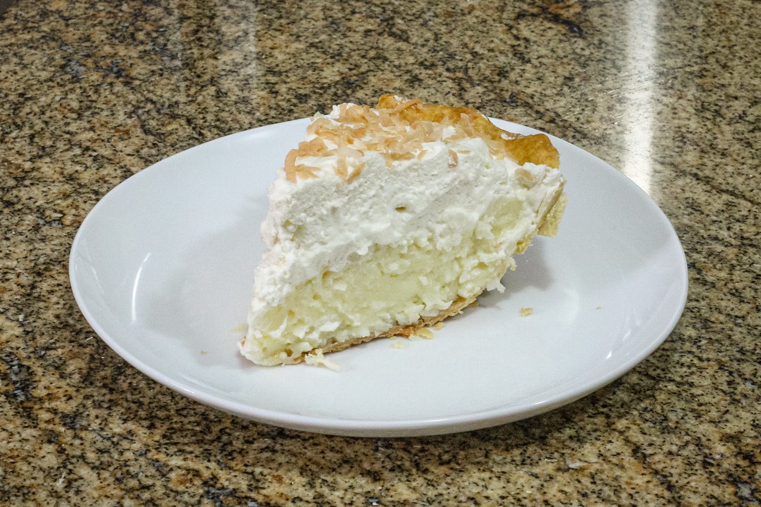 a slice of coconut cream pie with toasted coconut garnish