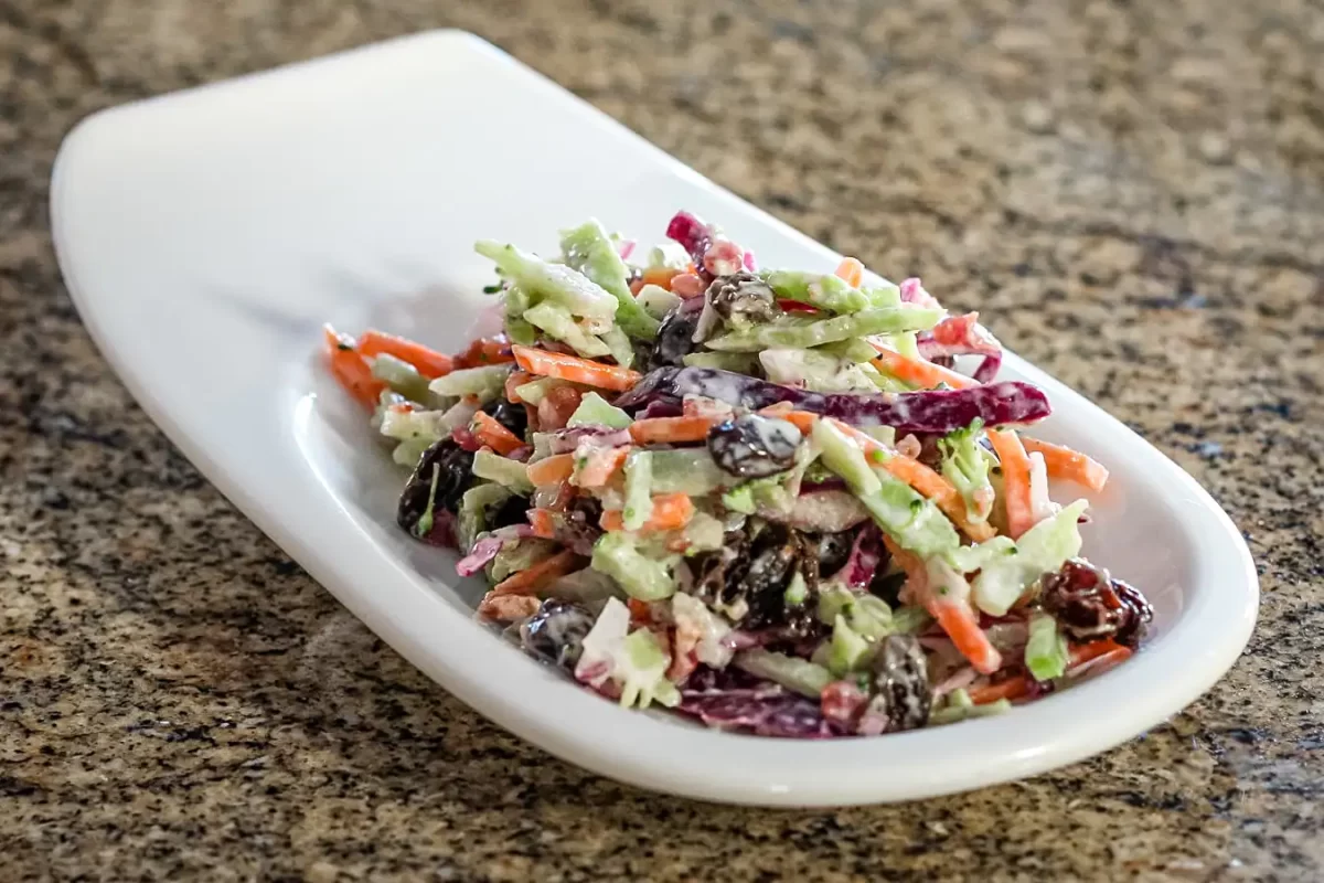 Fresh mixed vegetable salad with carrots, celery, and raisins on a white dish.