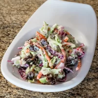 Creamy mixed vegetable salad garnished with dark sauce dressing.