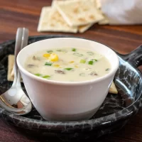 Creamy corn and beef soup served in a white bowl.