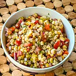 Fresh corn and vegetable salad in bowl with chopped herbs.