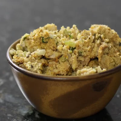 Crumbled tofu in a small brown bowl on dark countertop.