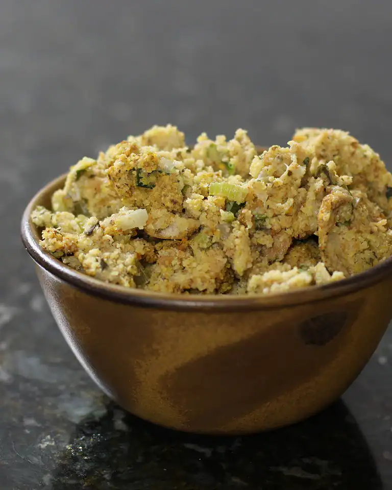 Crumbled tofu in a small brown bowl on dark countertop.