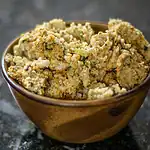 Seasoned breaded chicken pieces in a small brown bowl on dark surface.