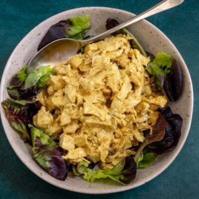 coronation chicken with curry powder in a lettuce-lined bowl