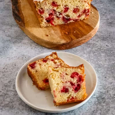 Moist cherry cake with white icing on top, sliced into pieces.