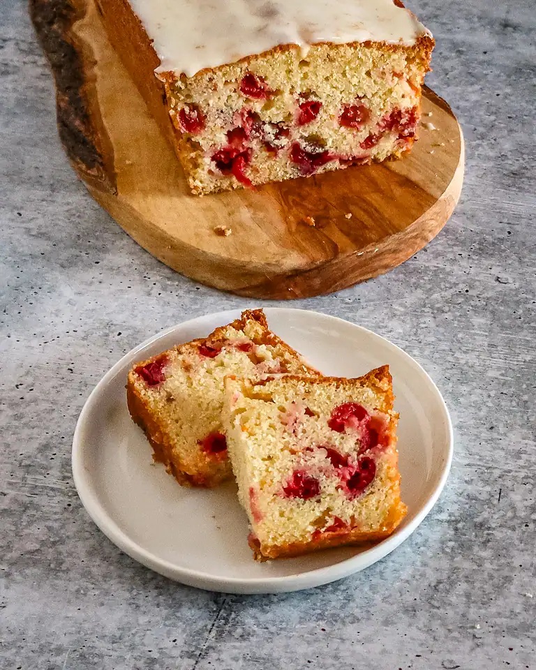 Moist cherry cake with white icing on top, sliced into pieces.