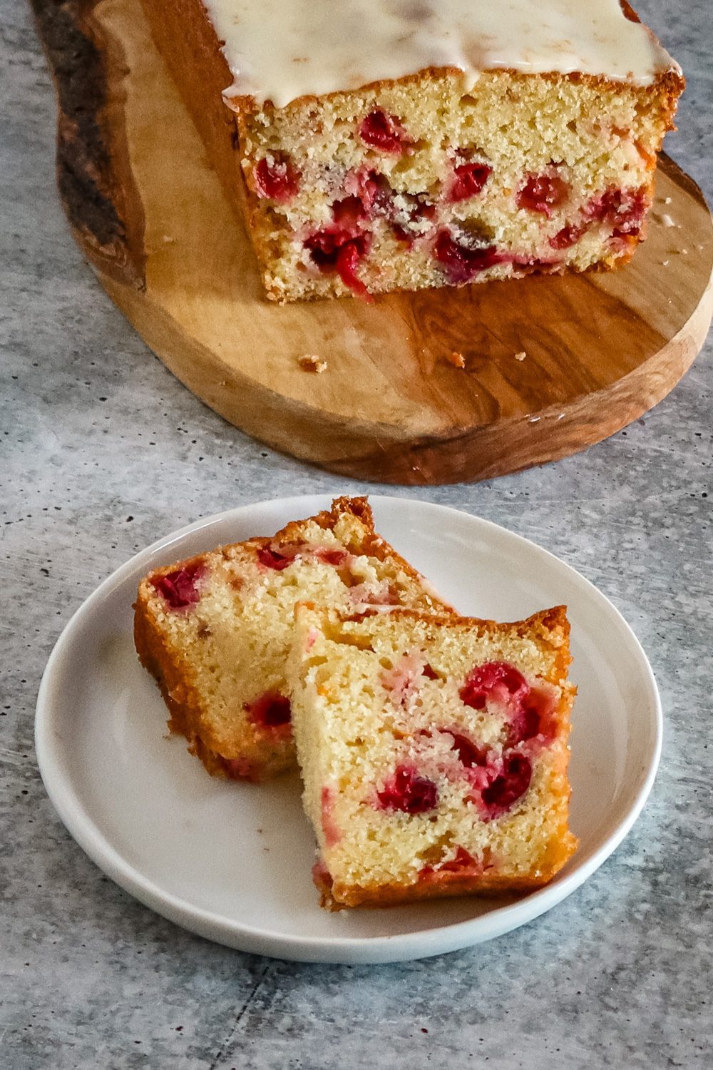 slices of cranberry orange bread on a plate with the loaf in the background