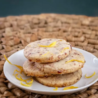 Rich fruit cookies with lemon zest on white plate.