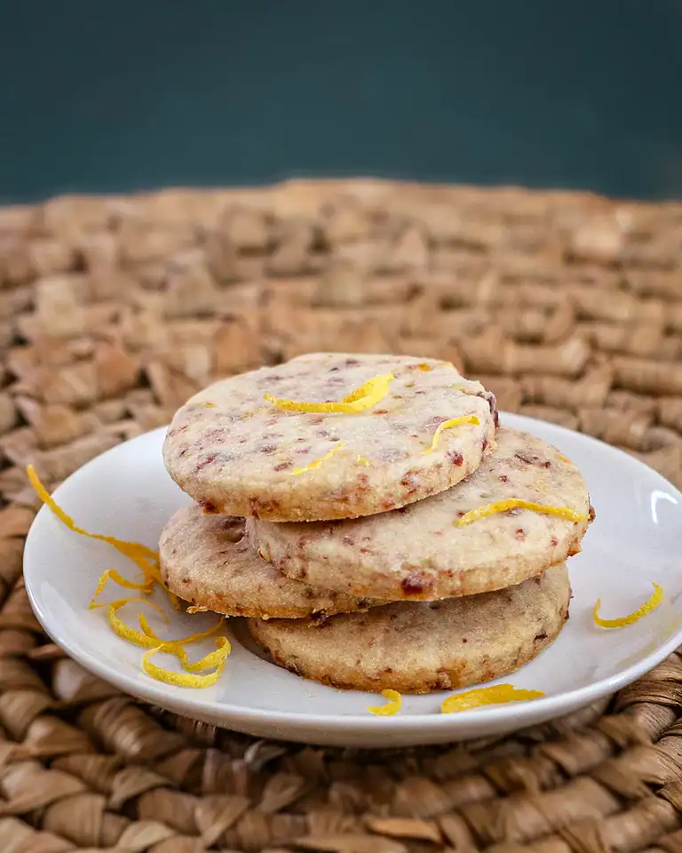Rich fruit cookies with lemon zest on white plate.