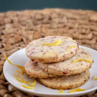 Cranberry orange shortbread cookies on a plate with strips of orange zest.