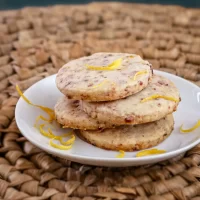 Lemon-flavored cookies garnished with lemon zest on a white plate.