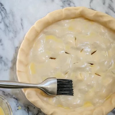Unbaked pie crust with filling and decorative slits on top.