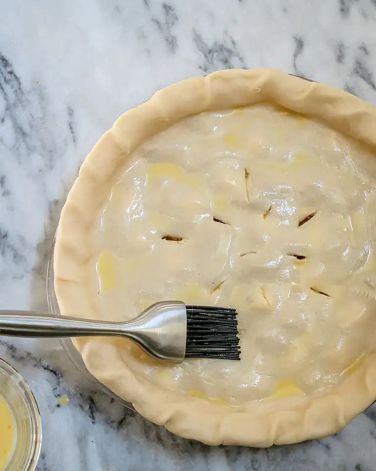 Unbaked pie crust with filling and decorative slits on top.