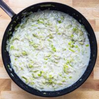 Creamy leek and garlic sauce in a black skillet.